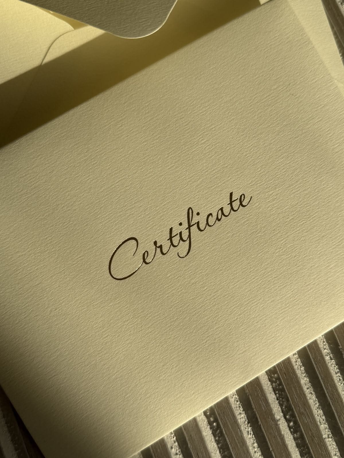 Krem rengi kâğıt üzerinde el yazısıyla Certificate yazan belge
